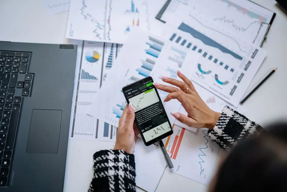 creative-03 An individual at a home office is using a smartphone to review stock market data.